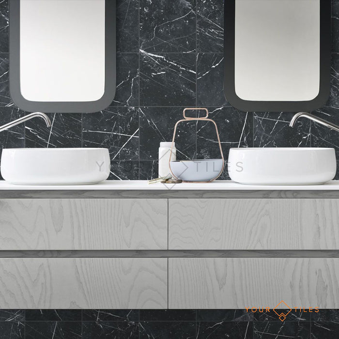 Modern bathroom featuring Florence Marquina Black 25x25cm marble-effect porcelain wall tiles, creating a bold black backdrop with white veining, styled with a floating vanity, twin countertop basins and minimalist fittings for a sleek, contemporary finish.