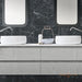 Modern bathroom featuring Florence Marquina Black 25x25cm marble-effect porcelain wall tiles, creating a bold black backdrop with white veining, styled with a floating vanity, twin countertop basins and minimalist fittings for a sleek, contemporary finish.