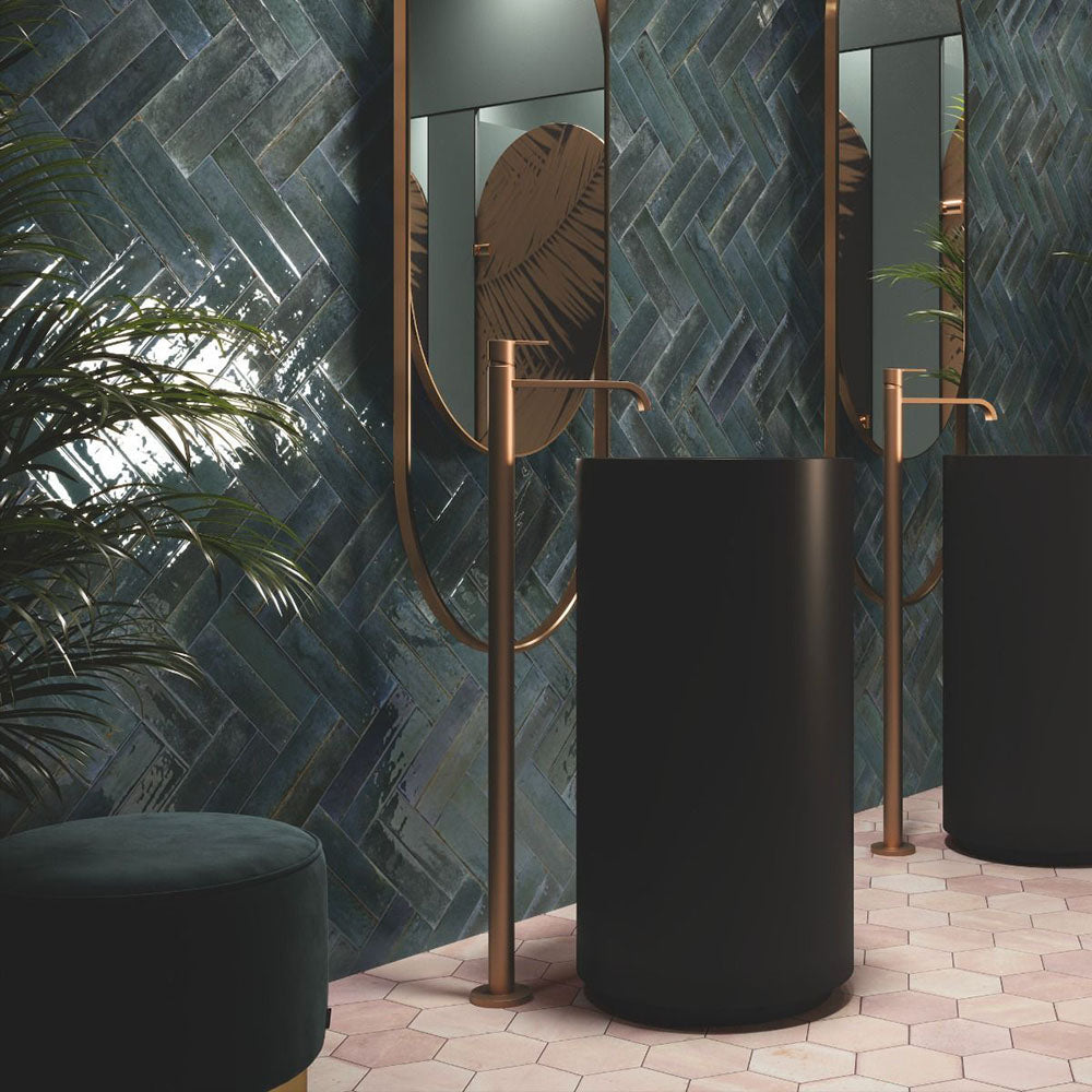 Bathroom wall featuring Allegra Blue Gloss Brick ceramic tiles in a 6 × 25cm format, laid in a herringbone pattern to create a bold, contemporary look with deep blue tones and a glossy finish.