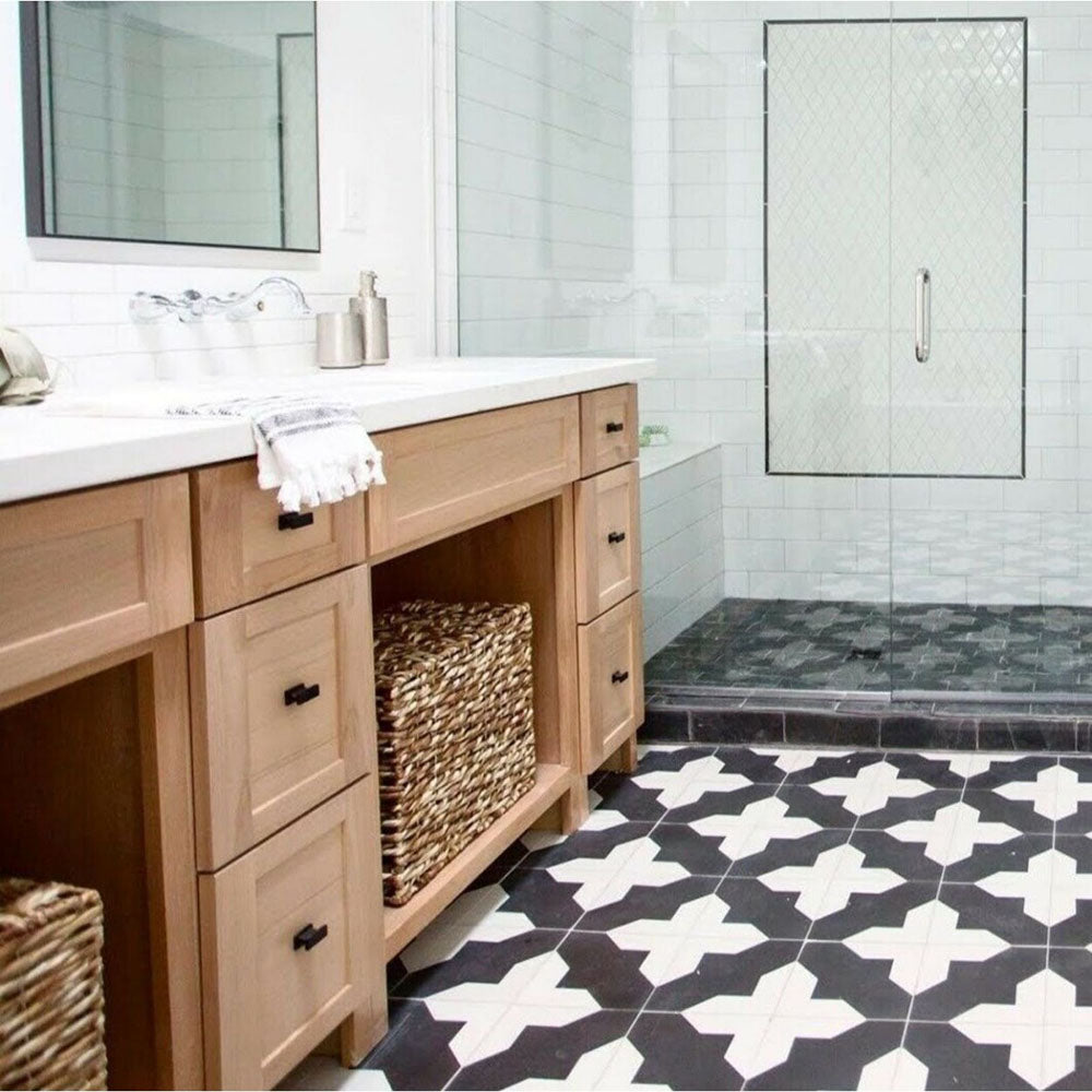 Bathroom featuring Almeria Cathedral Moroccan-style porcelain floor tiles in a bold black and white geometric pattern, 20x20cm, paired with light wood vanity units and white wall tiles.