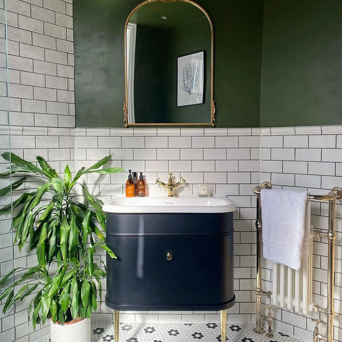 Bathroom featuring Pimlico White 7.5 × 15cm ceramic wall tiles with a crackle glaze finish, laid in a classic brick pattern and paired with a dark vanity, brass fittings and green walls.