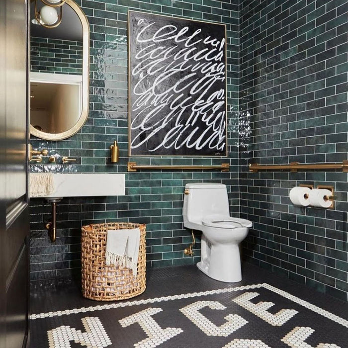 Bathroom featuring Zellige Royal Green Brick 6.5 × 20cm Moroccan-style ceramic wall tiles in rich deep green tones, laid in a horizontal brick layout throughout the space, paired with brass fittings, a wall-mounted basin and graphic floor tiles for a bold, characterful zellige-effect finish.