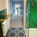 Bathroom interior featuring London Streets Baker Street 20x20cm Victorian Moroccan style floor tiles, styled with glossy green metro wall tiles, brass towel rail and glass shower enclosure, creating a decorative patterned bathroom floor.