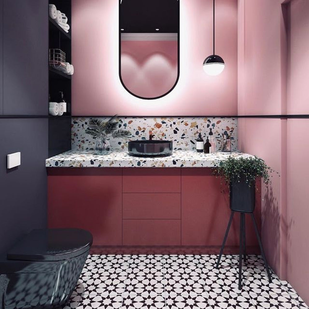 Bathroom setting featuring Agadir Black & White Mini Moroccan-style 15x15cm porcelain floor tiles, showcasing a bold geometric star pattern in black and white, styled with a modern vanity, terrazzo worktop and soft pink walls.