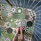 Bathroom featuring Fayrouz Verde Hexagon Patchwork Moroccan-style porcelain tiles in an 18.7×21.6cm hexagon format, combining intricate geometric and star patterns in layered green, sage and charcoal tones, paired with deep blue glazed wall tiles, brushed brass fixtures and a curved walk-in shower for a bold, character-led finish.
