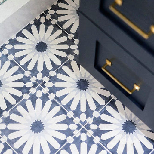 Souk Blue B Moroccan style 20x20cm patterned porcelain tile laid on a diagonal, featuring a bold geometric starburst design in deep blue and soft white, styled with navy cabinetry and brushed brass handles for a classic statement floor.