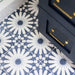 Souk Blue B Moroccan style 20x20cm patterned porcelain tile laid on a diagonal, featuring a bold geometric starburst design in deep blue and soft white, styled with navy cabinetry and brushed brass handles for a classic statement floor.