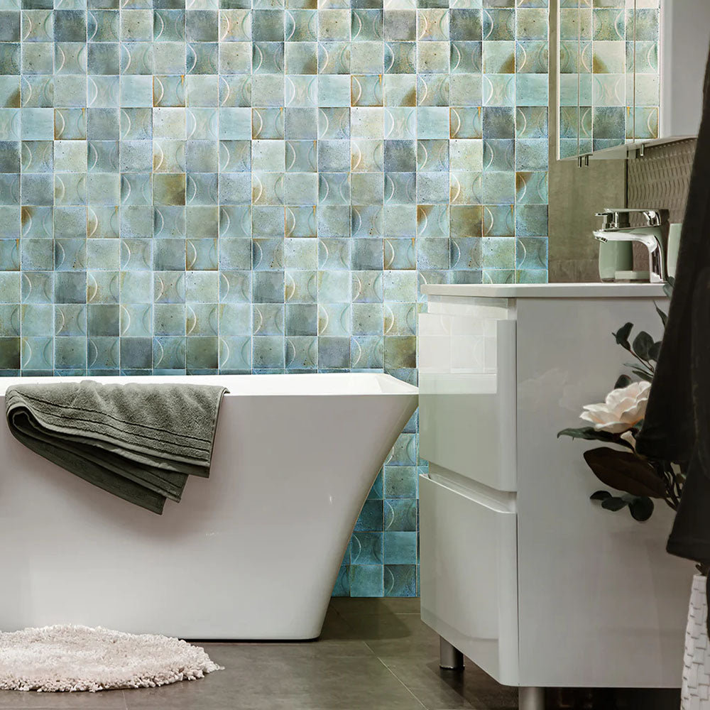 Bathroom feature wall clad in Saigon Celadon Green Decor Square Wall tiles, showcasing Moroccan-style 10 × 10cm glossy ceramic tiles in soft green and blue tones with a decorative relief pattern, styled with a freestanding bath and modern vanity.