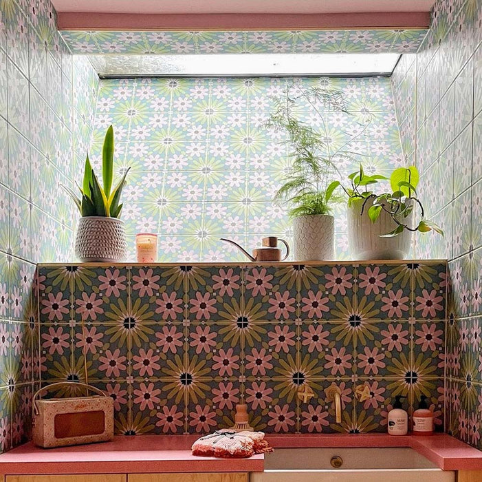 Bathroom vanity splashback featuring Fez Summer 20x20cm Moroccan-style porcelain tiles, showcasing a colourful geometric star pattern in soft green, blue and blush pink tones, paired with a pink worktop, brass tapware and indoor plants for a bold, characterful finish.