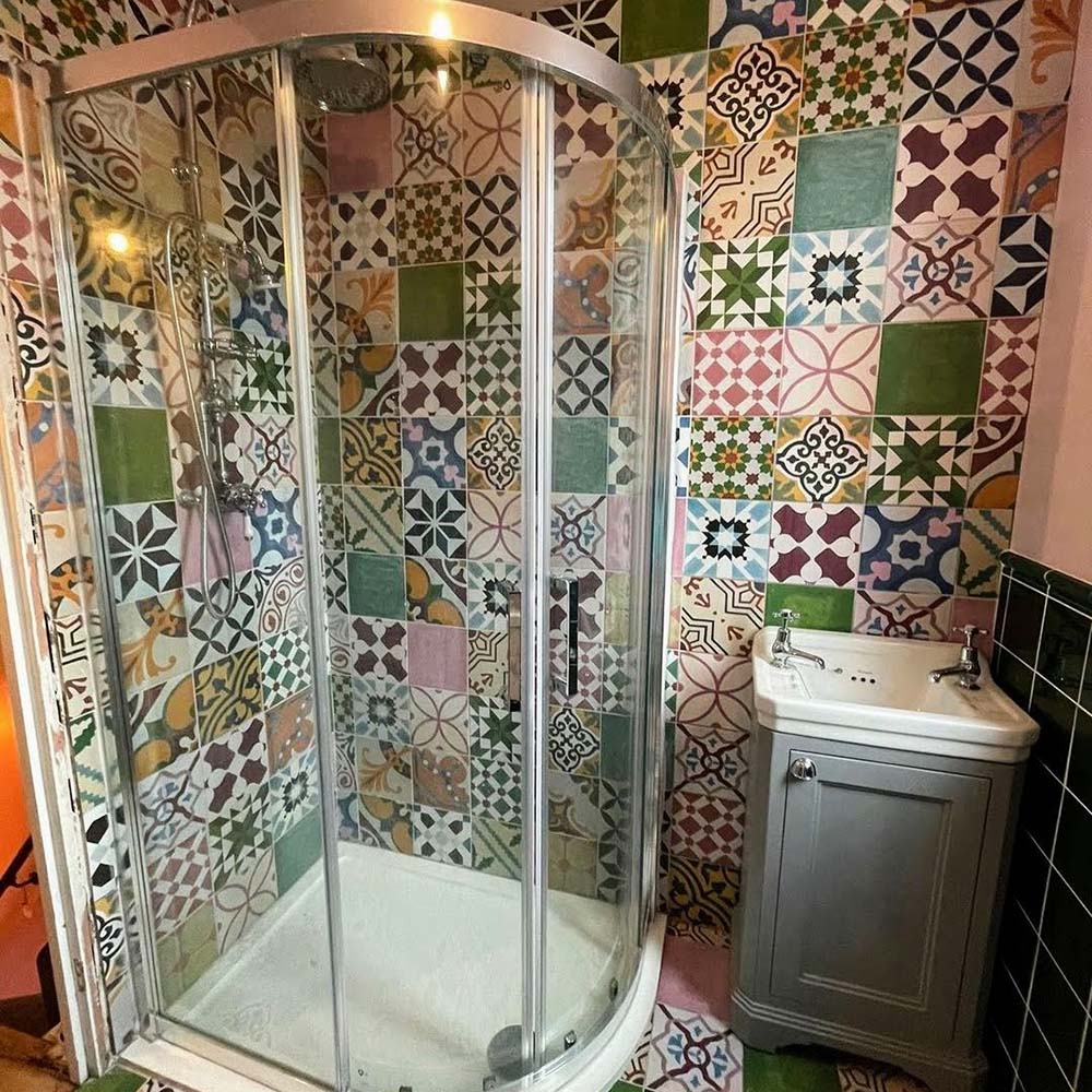 Bathroom interior featuring Fayrouz Patchwork 20×20cm Moroccan-style porcelain wall tiles, showcasing a vibrant mix of colourful geometric and floral patterns arranged in a bold patchwork design.