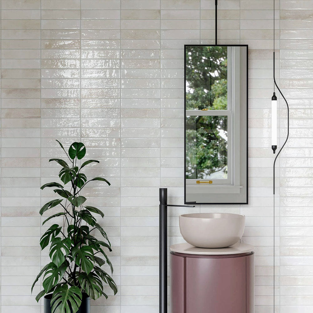 Bathroom wall featuring Allegra Blanca Gloss Brick ceramic tiles in a 6 × 25cm format, creating a clean, contemporary look with a glossy white finish behind a modern basin and mirror.