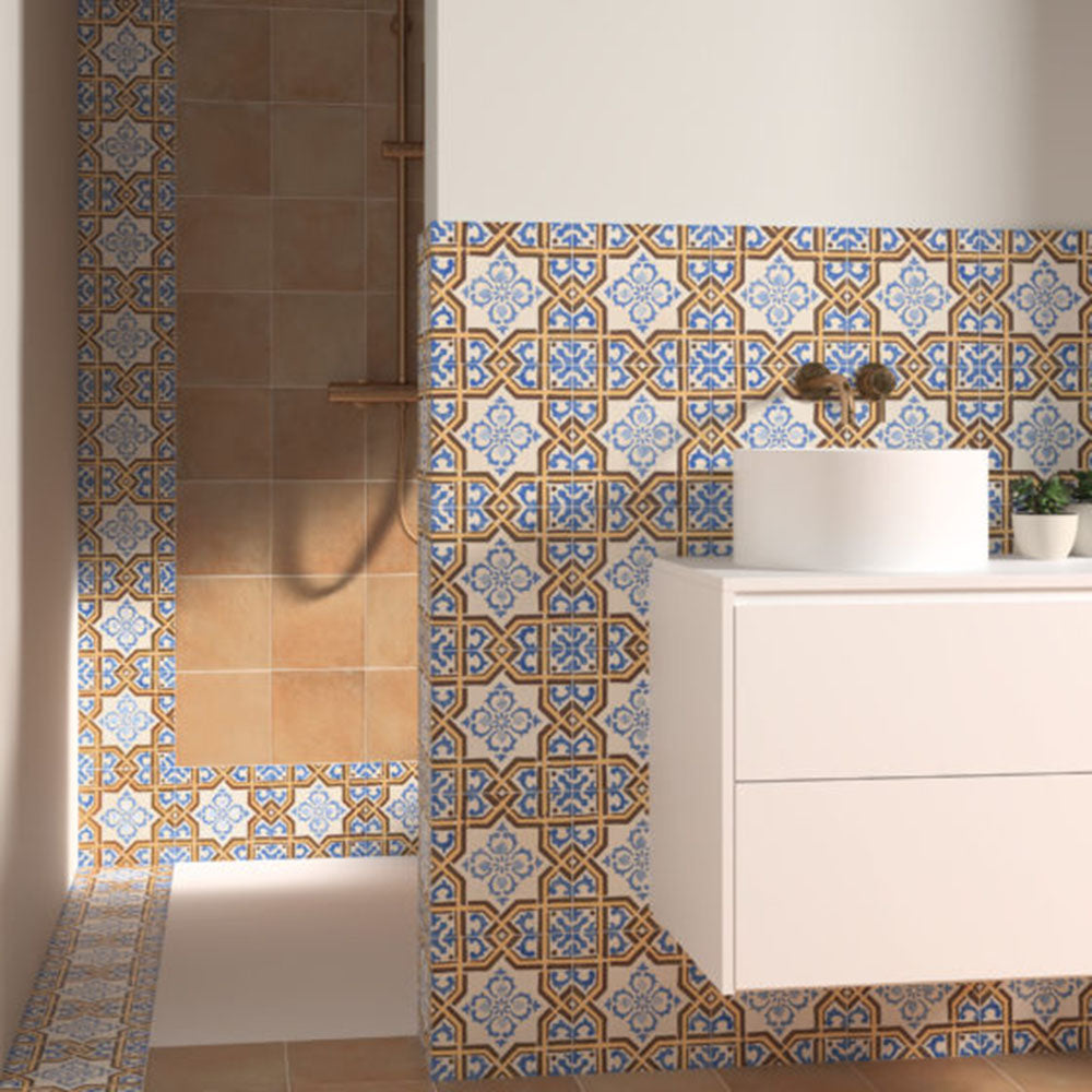 Victorian-style bathroom featuring Viscount Maestro 20×20cm porcelain wall and floor tiles with an ornate geometric pattern in blue, white and warm ochre tones, used as a decorative feature around the basin and shower area, paired with neutral wall tiles and a modern white vanity unit.