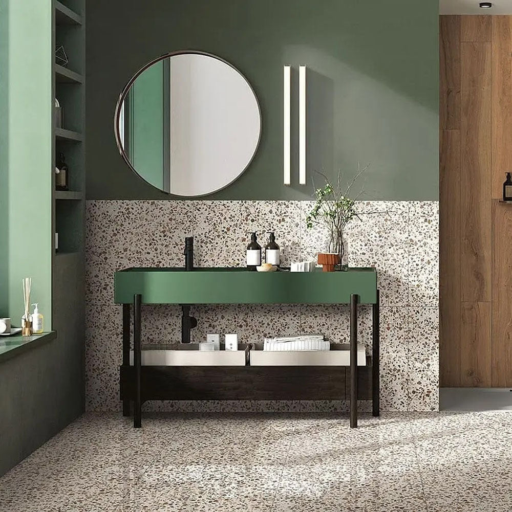 Bathroom featuring Turin Terrazzo Blanco Drops porcelain tiles in a 20 × 20cm format, displaying a light terrazzo-style design with fine scattered stone fragments, used across the floor and lower wall and paired with green cabinetry, black fixtures and warm wood accents for a calm, contemporary look.
