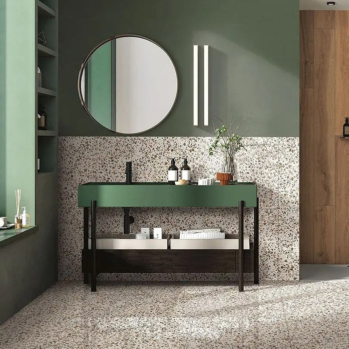 Bathroom featuring Turin Terrazzo Blanco Drops porcelain tiles in a 20 × 20cm format, displaying a light terrazzo-style design with fine scattered stone fragments, used across the floor and lower wall and paired with green cabinetry, black fixtures and warm wood accents for a calm, contemporary look.