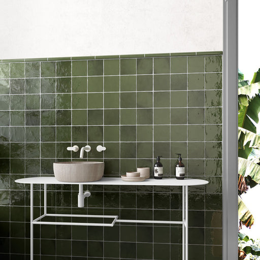 Bathroom vanity area featuring Zellige Botanical Green Square 13.2 × 13.2cm Moroccan-style ceramic wall tiles, laid in a neat grid pattern with rich green tones, a glossy handcrafted zellige-effect finish and subtle tonal variation, creating a fresh, natural and contemporary backdrop.