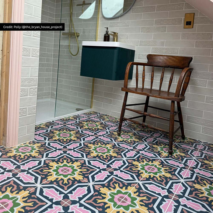 Bathroom interior featuring Cuba Havana Moroccan-style porcelain floor tiles in a 20×20cm format, laid in a repeating geometric pattern with navy, pink, green and mustard tones, paired with soft grey brick-effect wall tiles, a teal vanity unit and brass fixtures for a bold yet balanced finish.