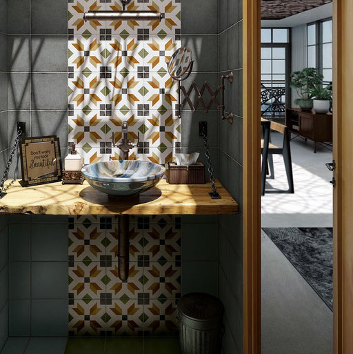 Victorian-style bathroom featuring Viscount High Street 20×20cm porcelain wall and floor tiles with a geometric pattern in olive green, mustard and charcoal tones, styled as a statement splashback behind a ceramic basin with a rustic wooden countertop, vintage-style fittings and dark green wall tiles.