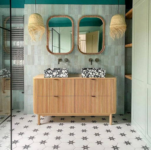 Bathroom featuring Polaris Black Star Hexagon Moroccan-style porcelain floor tiles in a 22 × 25cm format, laid in a striking star pattern and paired with a wooden vanity unit, terrazzo basins and soft green wall tiles for a warm, contemporary bathroom design.