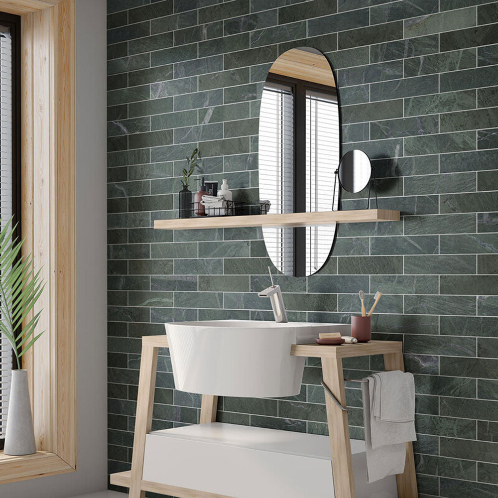 Bathroom interior featuring Fayrouz Verde 5x20cm natural marble tiles with a honed finish, installed in a horizontal brick layout, styled with a wooden vanity unit, oval mirror and soft neutral accessories.