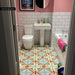 Bathroom interior featuring Cuba Star Moroccan-style porcelain floor tiles in a 20×20cm square format, laid in a repeating geometric star pattern with soft green, blue, pink and mustard tones, paired with white metro wall tiles and blush pink walls for a fresh, characterful finish.