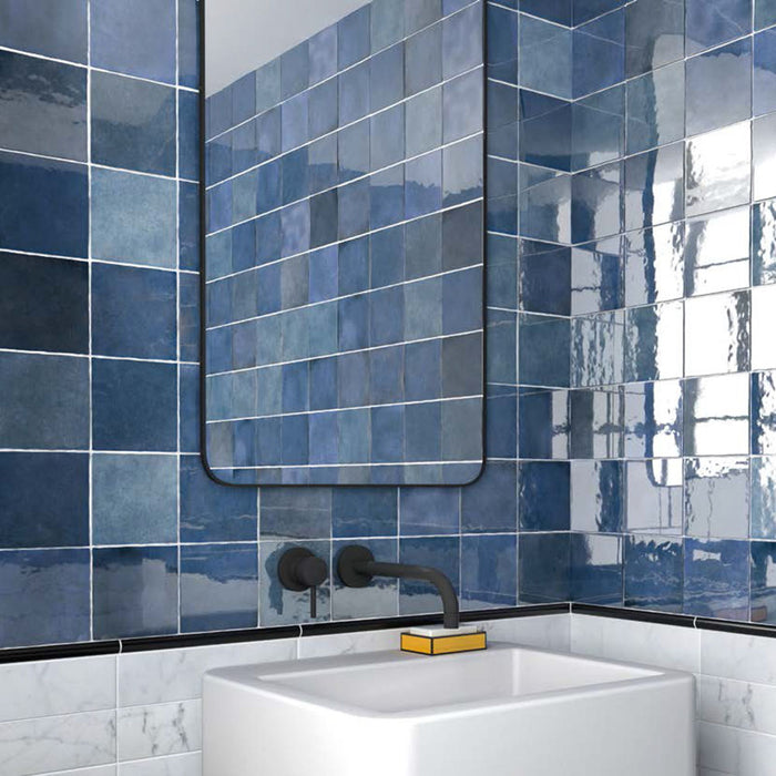 Bathroom featuring Zellige Royal Blue 13.2×13.2cm Moroccan-style ceramic square tiles installed on the walls, showcasing rich blue tones with a glossy handmade-look finish, paired with matte black tapware, a minimalist basin and a contemporary mirror.