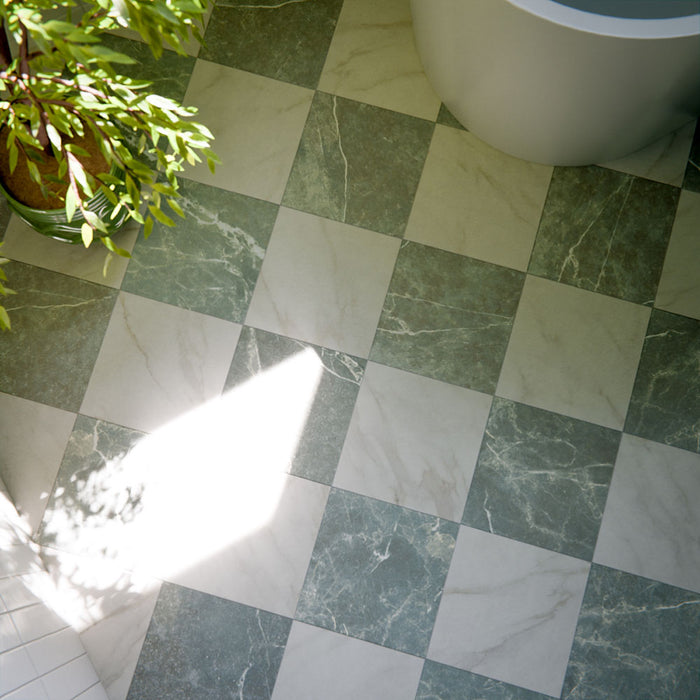 Bathroom floor featuring Vitoria Classic Bianco white marble-style porcelain chequerboard tiles in a 30 × 30cm format, combining soft white and muted green marble-effect squares laid in a classic pattern, styled with a freestanding bath, natural light, and greenery for a fresh, elegant finish.