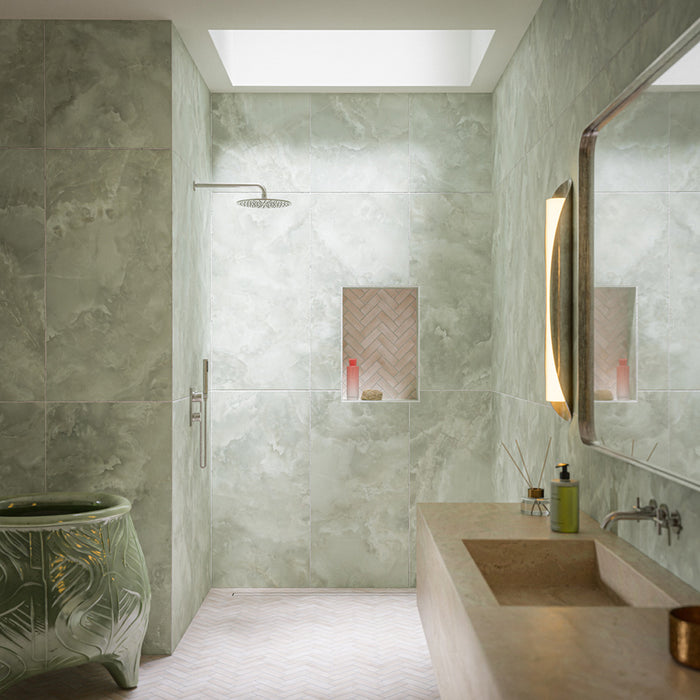 Contemporary shower room featuring Benomar Canvas Moroccan style matt mini brick tiles in 5cm x 15cm. Soft cream herringbone tiles create a feature shower niche, complemented by green onyx effect porcelain wall tiles, a stone vanity, and calming spa-inspired styling.