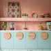 Kitchen featuring Benomar Pink Gloss 5x15cm Moroccan-style wall tiles in a geometric layout, styled with pastel blue cabinetry, brass fixtures, and decorative accents for a playful contemporary interior.