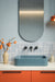 Bathroom featuring Berber Tetuan Blue 15cm x 15cm Moroccan style patterned tiles across the walls and floor, showcasing an intricate blue and white design, paired with a blue basin, orange vanity and coordinating statement lighting.