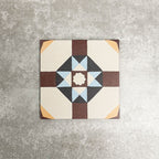 Single London Streets Berlin Street 20x20cm Victorian Moroccan style porcelain tile displayed in a product setting, featuring a geometric star pattern in burgundy, soft blue, charcoal and cream tones inspired by traditional decorative floor tiles.