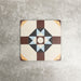 Single London Streets Berlin Street 20x20cm Victorian Moroccan style porcelain tile displayed in a product setting, featuring a geometric star pattern in burgundy, soft blue, charcoal and cream tones inspired by traditional decorative floor tiles.