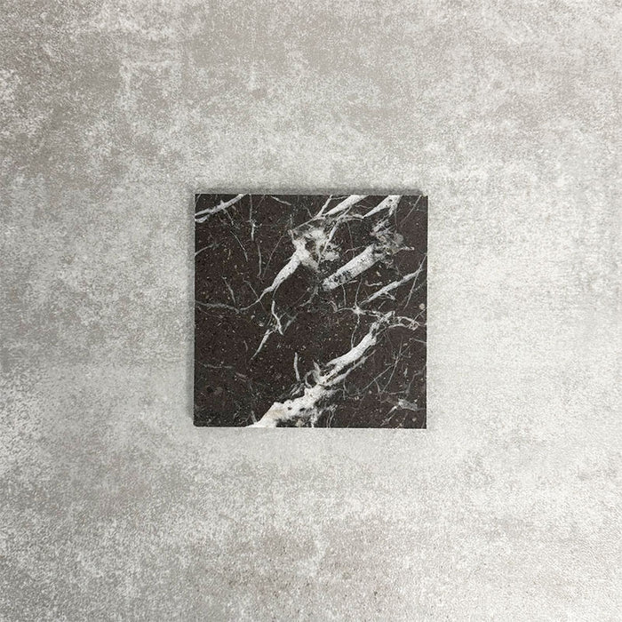 Single Fayrouz Black 15.2x15.2cm natural marble tile with a honed finish, featuring deep black tones and bold white veining, displayed against a neutral textured background in a clean product setting.