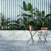 Outdoor patio featuring Boho Ocean Blue 2cm Patterned Outdoor Slabs 49.75cm x 99.55cm, with soft blue tonal variation, paired with striped wall tiles, lush greenery and contemporary garden furniture.
