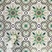 Group of London Streets Bond Street 20x20cm Victorian Moroccan style porcelain tiles arranged to showcase the repeating geometric pattern in green, black and cream tones, styled with white flowers in a decorative flat-lay setting.