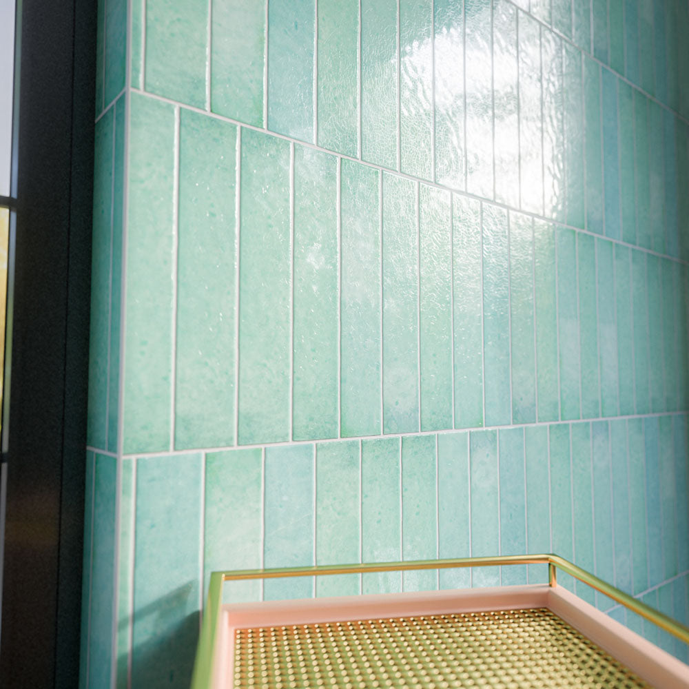 Bora Bora Aqua Brick 6.5cm x 32.8cm wall tiles, highlighting the softly textured flux glaze finish and subtle tonal variation as the glossy surface catches the light.