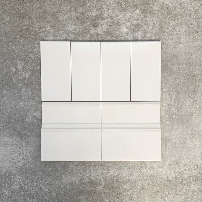 Pimlico White 7.5 × 15cm ceramic wall tiles with a crackle glaze finish, paired with matching 15 × 15cm skirting tiles to create a classic brick layout with a decorative base detail.