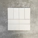 Pimlico White 7.5 × 15cm ceramic wall tiles with a crackle glaze finish, paired with matching 15 × 15cm skirting tiles to create a classic brick layout with a decorative base detail.