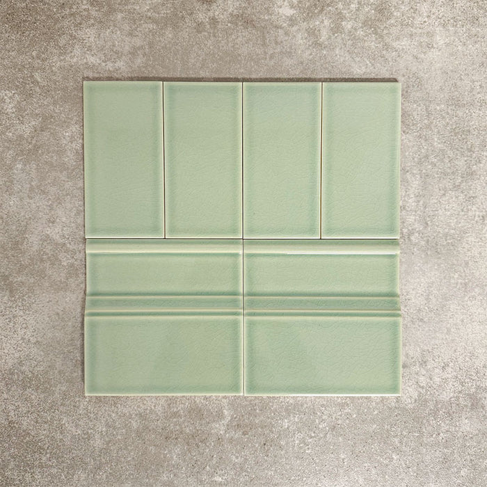 Pimlico Lime Green 7.5 × 15cm ceramic wall tiles with a crackle glaze finish, paired with matching 15 × 15cm skirting tiles to create a classic brick layout with a decorative base detail.