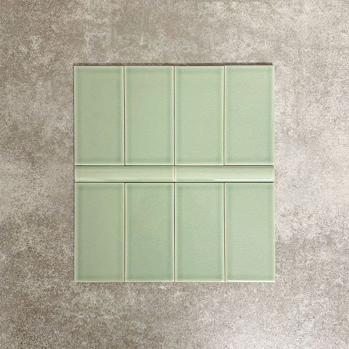 Pimlico Lime Green 7.5 × 15cm ceramic wall tiles with a crackle glaze finish, paired with matching 2.5 × 15cm pencil trim to create a classic brick layout with a neat, decorative horizontal detail.
