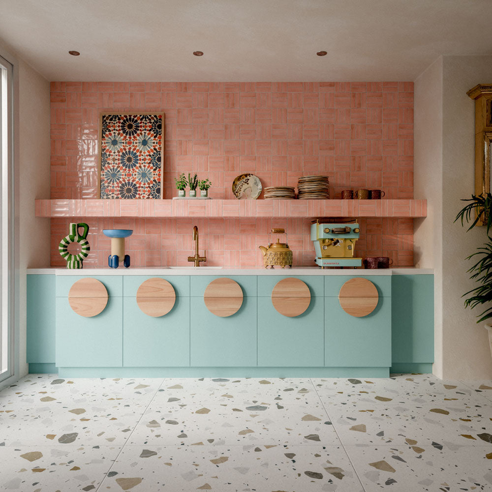 Kitchen featuring Byblos Cotton 60x120cm terrazzo-effect porcelain floor tiles, paired with blush pink Moroccan-style wall tiles, pastel blue cabinetry, and brass fixtures for a playful contemporary interior.
