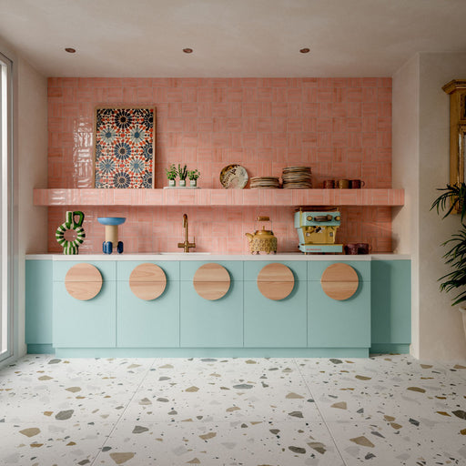 Kitchen featuring Byblos Cotton 60x120cm terrazzo-effect porcelain floor tiles, paired with blush pink Moroccan-style wall tiles, pastel blue cabinetry, and brass fixtures for a playful contemporary interior.