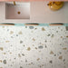 Kitchen featuring Byblos Cotton 60x120cm terrazzo-effect porcelain floor tiles, paired with blush pink Moroccan-style wall tiles, pastel blue cabinetry, and brass fixtures for a playful contemporary interior.