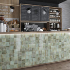 Commercial café counter clad in Saigon Celadon Green Square Wall tiles in a Moroccan-inspired style, featuring 10 × 10cm glossy ceramic tiles in soft green and blue-grey tones with natural colour variation.