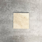 Single Fayrouz Latte Foam 15.2x15.2cm natural marble tile with a tumbled finish, featuring soft cream tones and gentle natural veining, displayed against a neutral textured background in a clean product setting.