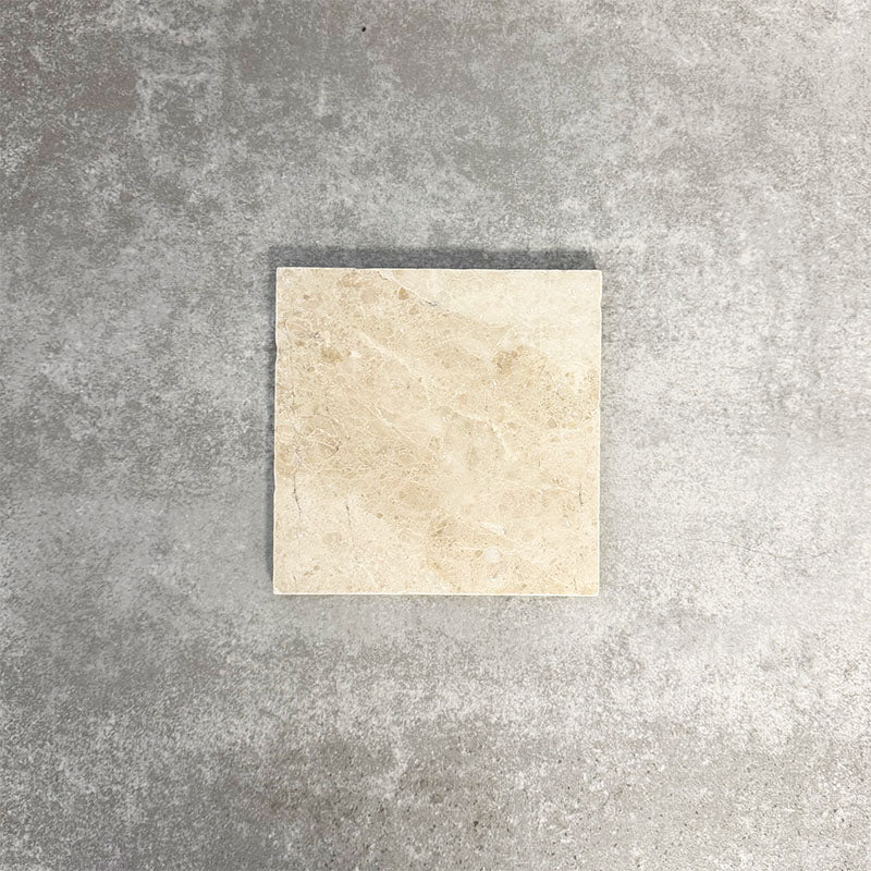 Single Fayrouz Latte Foam 15.2x15.2cm natural marble tile with a tumbled finish, featuring soft cream tones and gentle natural veining, displayed against a neutral textured background in a clean product setting.