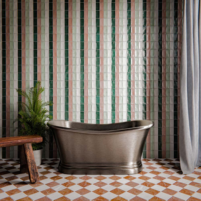 Bathroom interior featuring Dordogne glazed brick tiles in green, sage and blush tones installed vertically on the wall, styled with a freestanding metal bathtub and chequerboard floor tiles in an elegant spa-inspired setting.