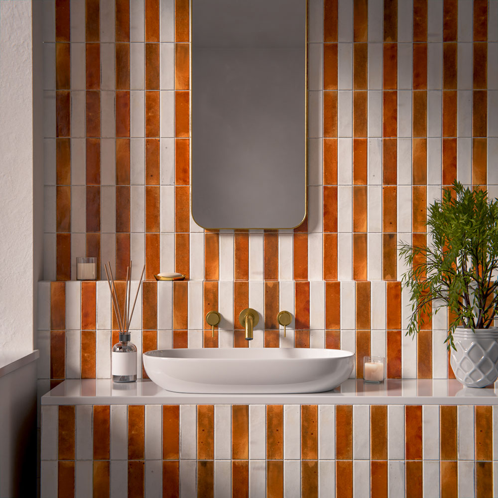 Bathroom vanity area featuring Saigon Amber and Saigon White brick tiles installed vertically in a striped layout, styled with a wall-mounted basin, brushed brass fittings, soft lighting, and greenery for a warm, contemporary look.