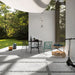 Outdoor patio setting featuring Comet Silver Stone 2cm 60 × 90cm porcelain tiles, laid in a modern grid with gravel joints. Soft silver-grey stone effect tones create a clean, contemporary look, complemented by minimalist furniture, greenery, and natural light.