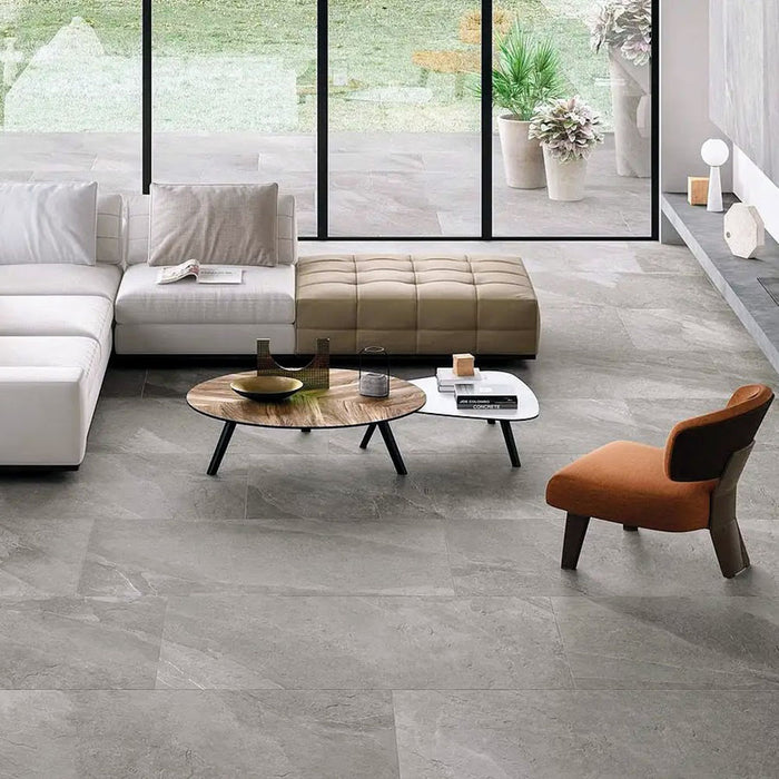 Living area featuring Comet Silver Stone 2cm 60 × 90cm porcelain tiles, showcasing soft silver-grey stone effect tones with subtle veining. Laid in a staggered pattern, the tiles create a calm, contemporary foundation, complemented by warm furnishings and natural light.