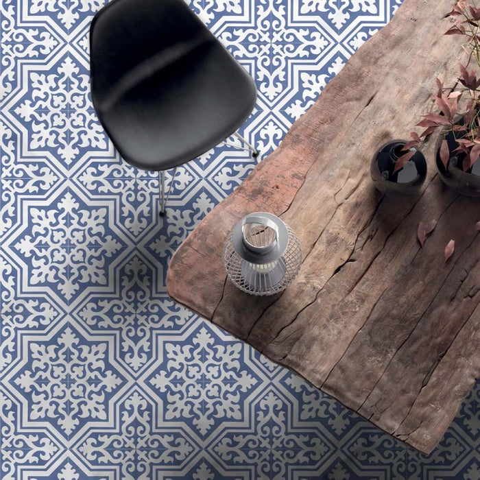 Dining room interior featuring London Streets Thornton Place 20x20cm Victorian Moroccan style porcelain floor tiles in soft blue and white tones, styled with a rustic wooden dining table, black chair and decorative accessories for a classic patterned floor design.